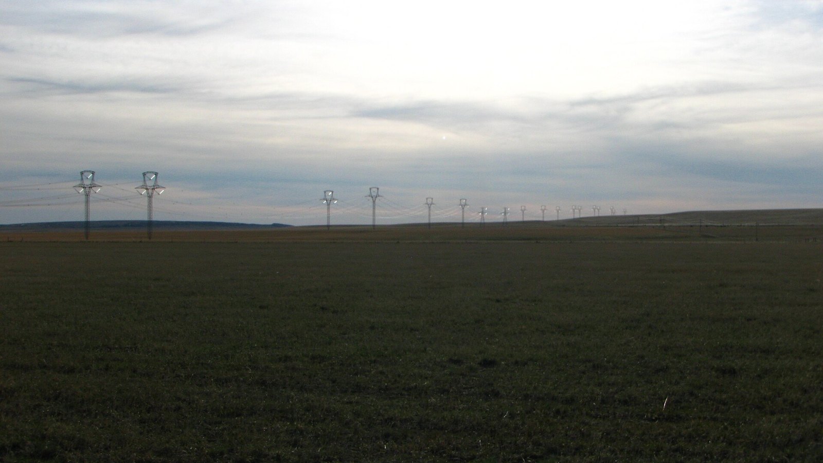 Two parallel overhead power lines crossing open grassland in central Montana